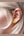 Gold heart-shaped earring worn by a person with blonde hair.