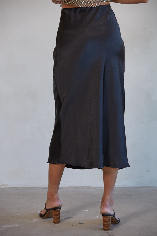 Person wearing a dark blue skirt with a plain background