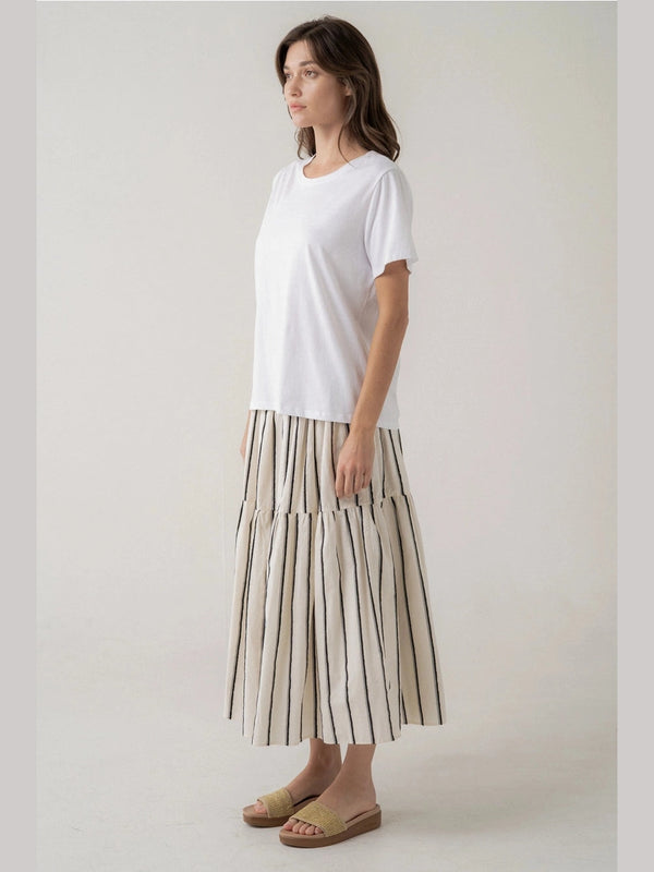 Woman wearing a white top and striped skirt on a plain background