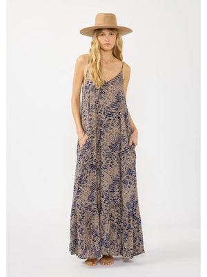 Woman wearing a long, patterned dress and a hat on a white background