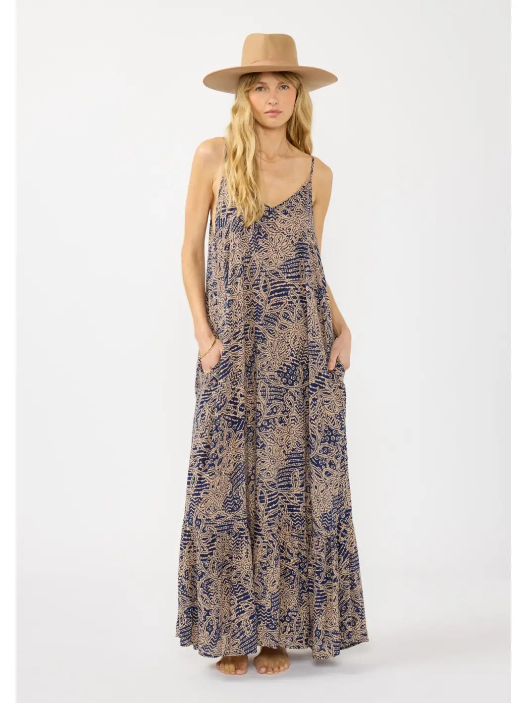 Woman wearing a long, patterned dress and a hat on a white background