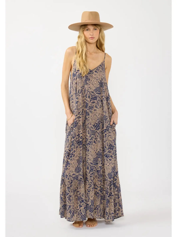 Woman wearing a long, patterned dress and a hat on a white background