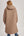 Person wearing a long quilted beige coat on a plain background