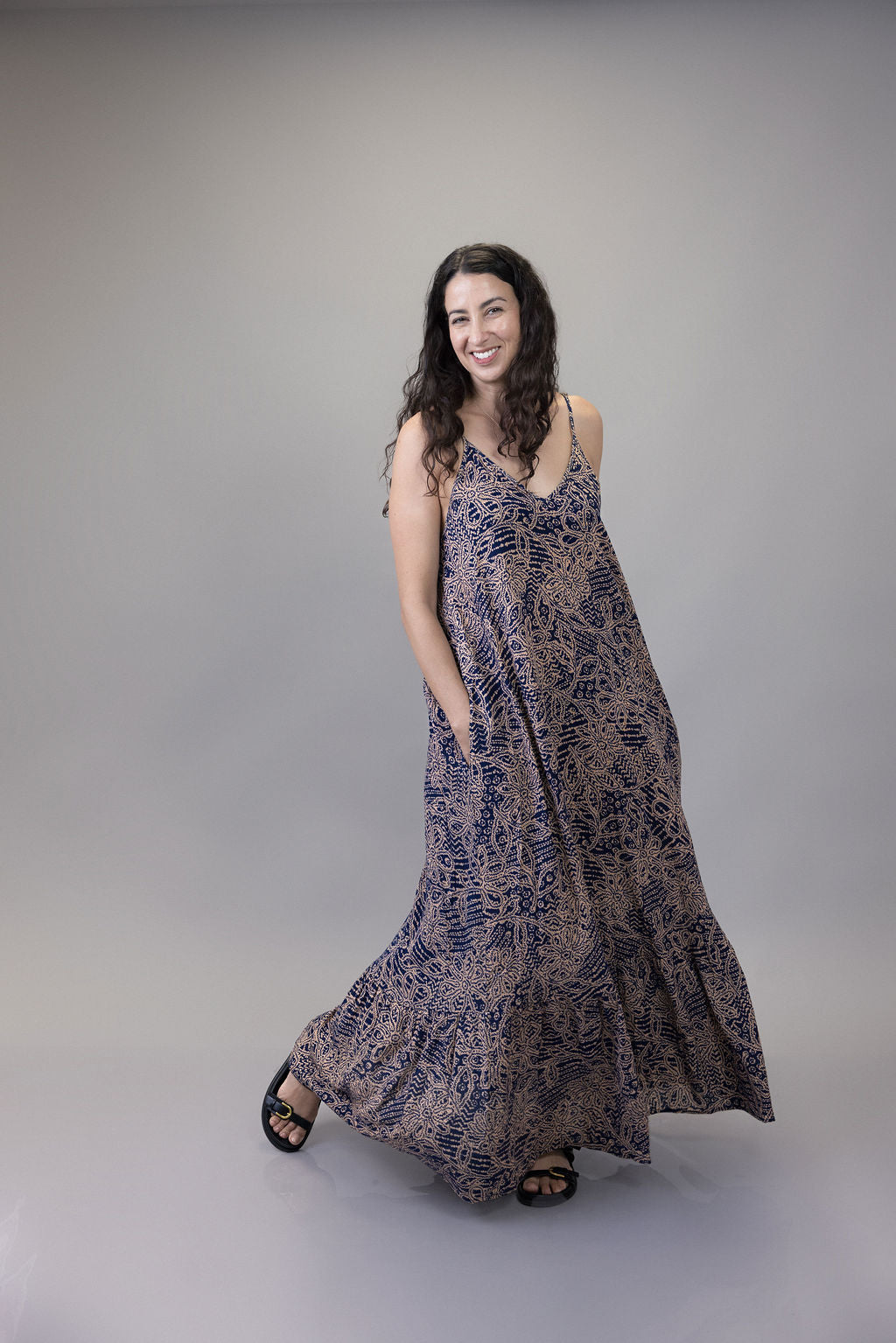 Woman wearing a long, patterned dress against a plain background