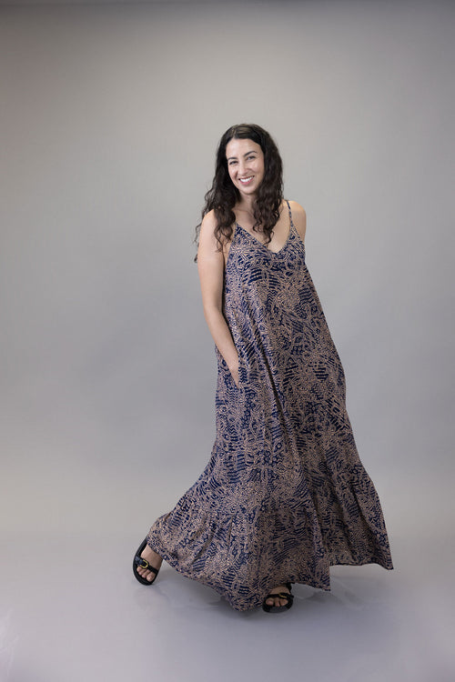 Woman wearing a long, patterned dress against a plain background