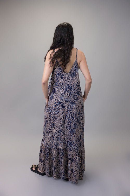 Woman wearing a long, patterned dress against a gray background