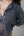 Person wearing a dark gray cardigan with button details on a neutral background