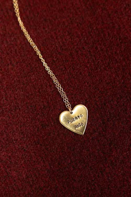 Gold heart-shaped pendant necklace with 'Puerto Rico' engraving on a red background