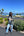 Person standing outdoors with a clear blue sky and plants in the background