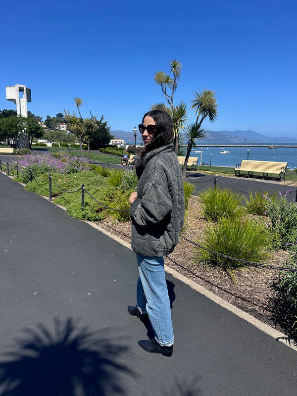 Person walking on a path with palm trees and a clear blue sky in the background