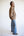 Person wearing a beige jacket and blue jeans on a white background