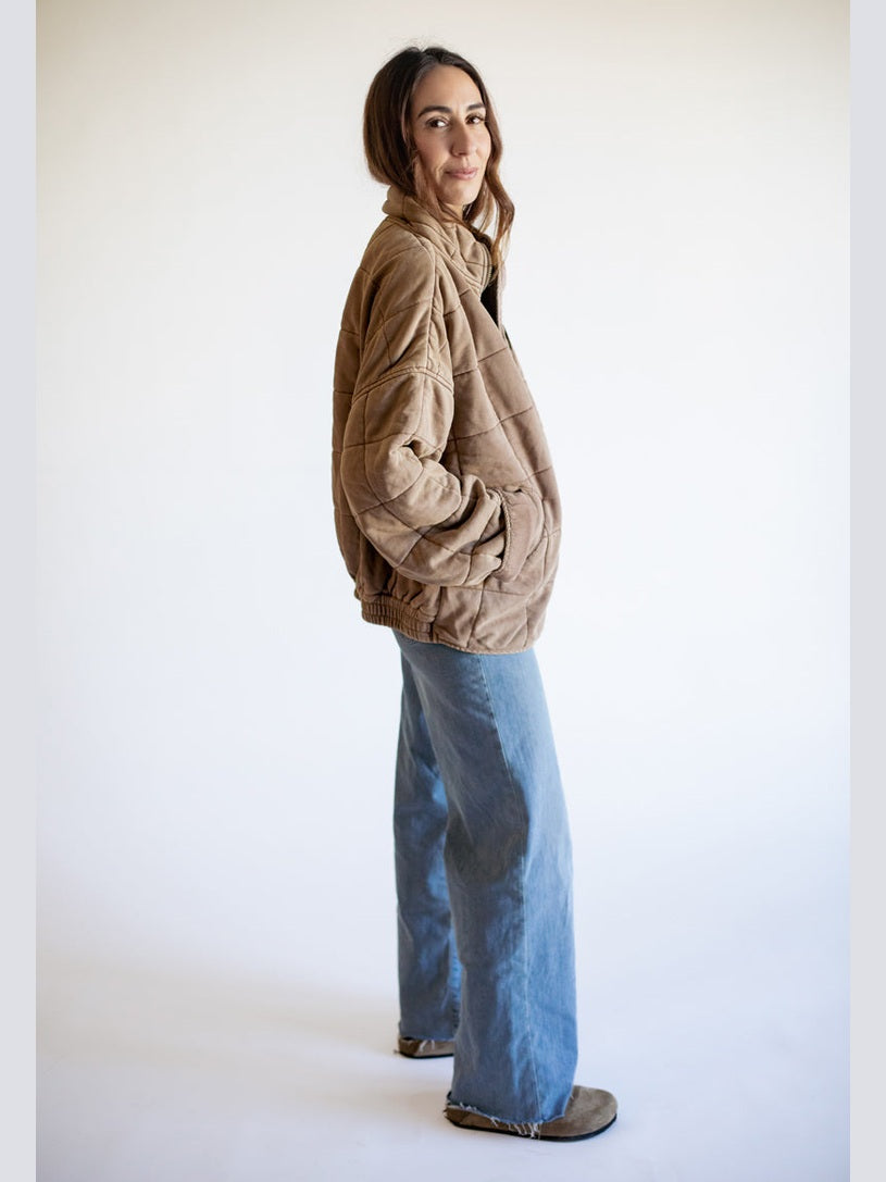 Person wearing a beige jacket and blue jeans on a white background