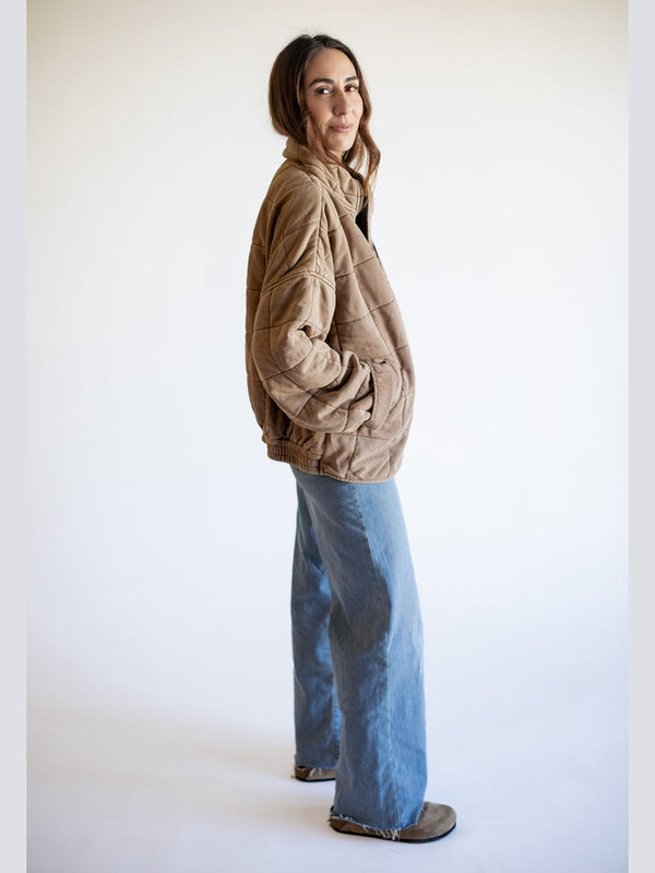 Person wearing a beige jacket and blue jeans on a white background