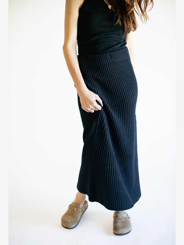 Person wearing a black ribbed knit skirt on a white background