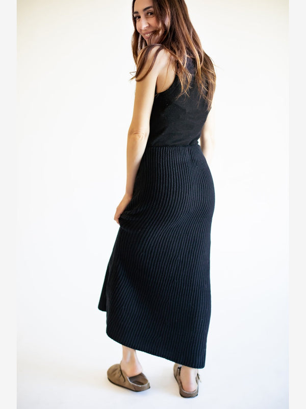 Woman wearing a black sleeveless dress against a white background