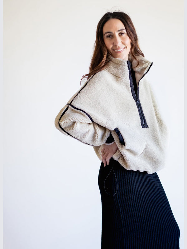 Woman wearing a white fleece pullover with black trim against a white background