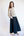 Woman wearing a beige sweater and navy skirt on a white background