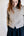 Woman wearing a light gray cardigan with a plain background