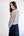 Woman wearing a light gray sweater and dark blue skirt against a white background