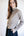 Woman wearing a beige turtleneck sweater against a plain background