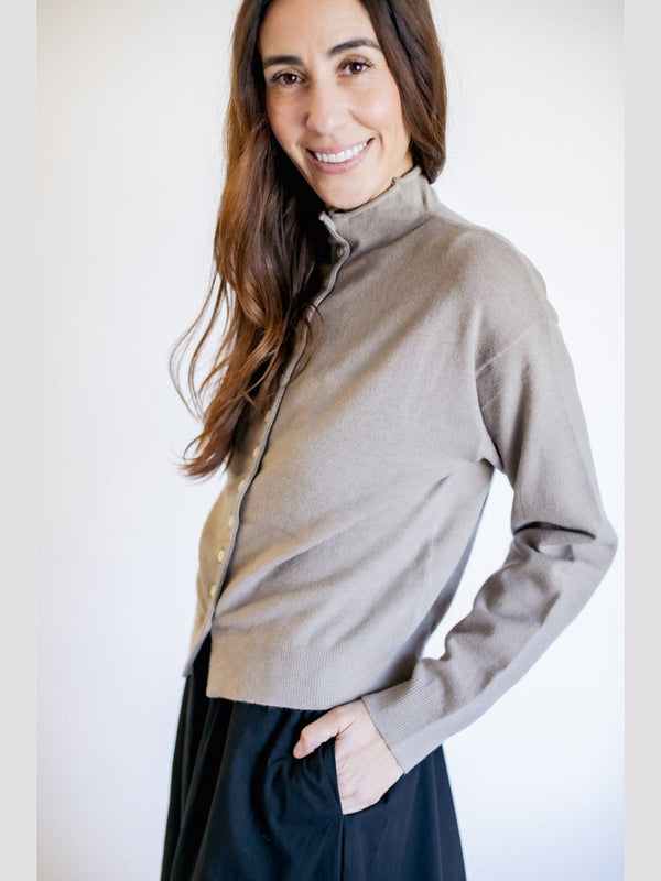Woman wearing a beige turtleneck sweater against a plain background