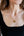 Gold heart-shaped necklace worn by a person with a black top