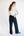 Woman wearing a cream sweater and black pants against a white background