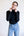 Person wearing a black turtleneck and light blue jeans against a white background