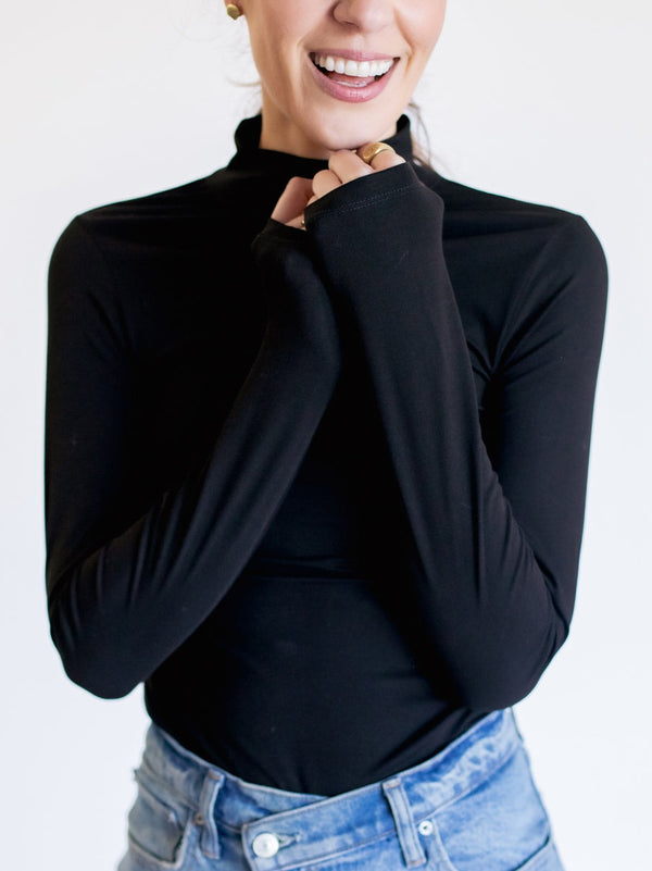 Person wearing a black long-sleeve top and blue jeans on a white background