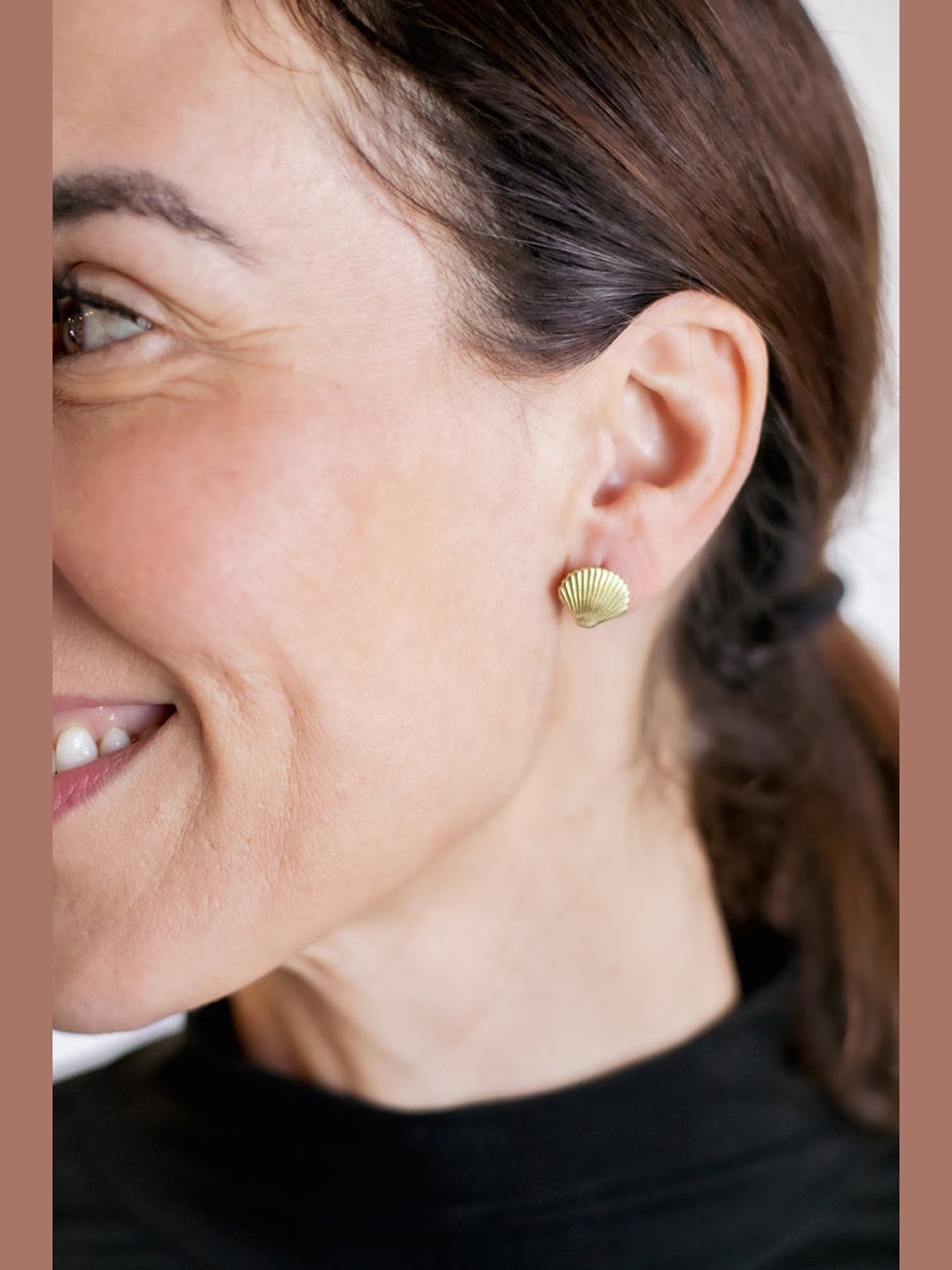 Close-up of a woman wearing gold shell-shaped earrings.