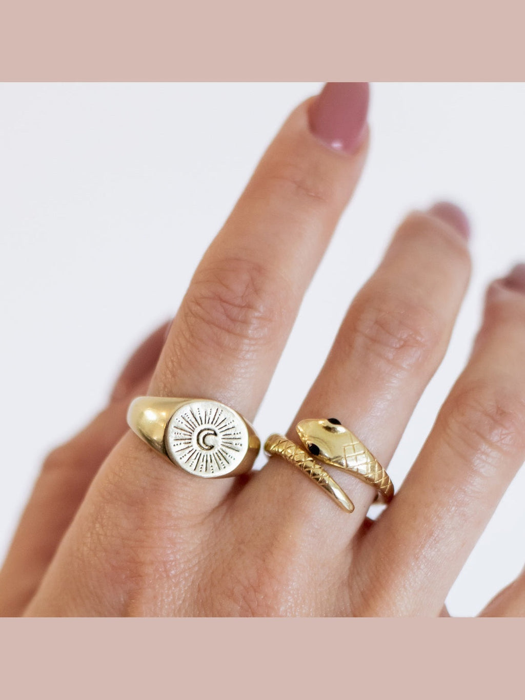 Gold ring with a moon design on a finger against a white background