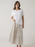 Woman wearing a white t-shirt and a long, striped skirt on a plain background