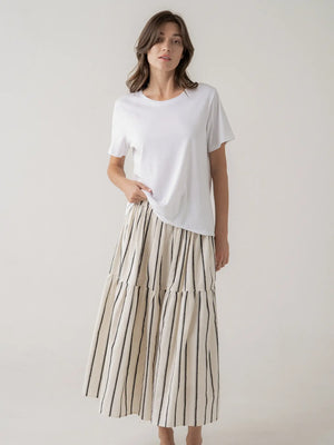 Woman wearing a white t-shirt and a long, striped skirt on a plain background