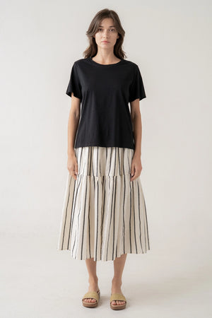 Woman wearing a black top and striped skirt on a white background