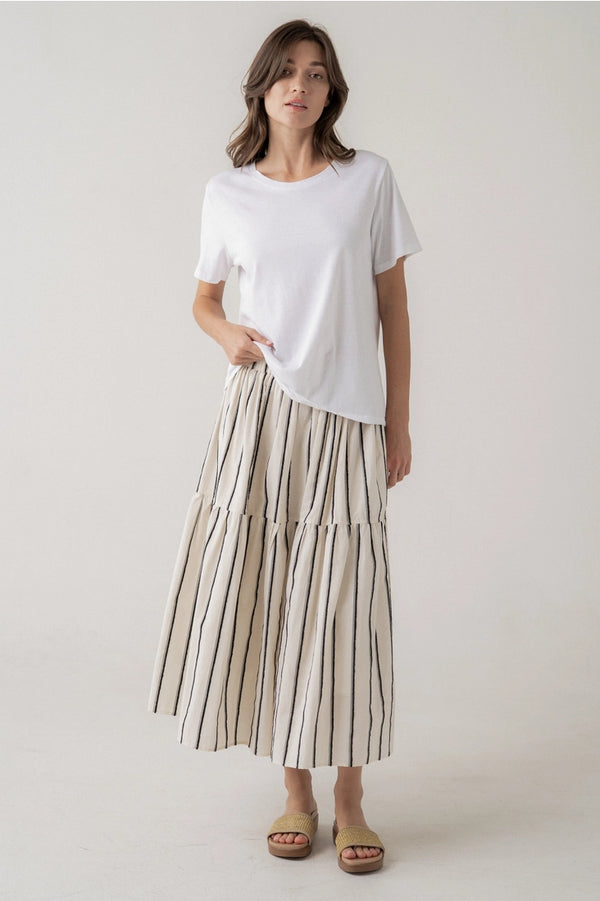 Woman wearing a white t-shirt and striped skirt on a plain background