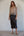 Woman wearing a sheer top and black skirt against a plain background