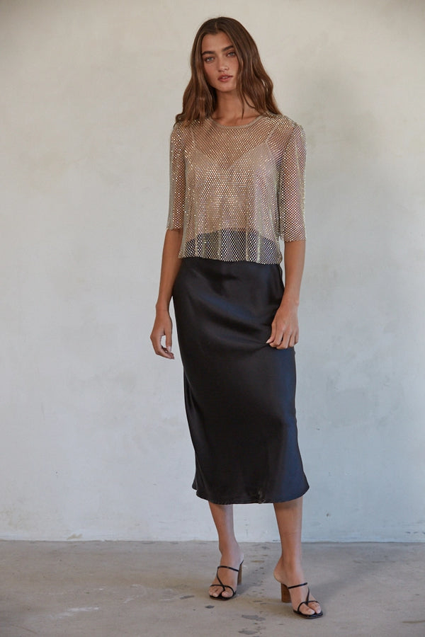 Woman wearing a sheer top and black skirt against a plain background