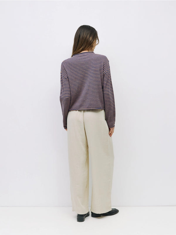 Person wearing a striped shirt and beige pants against a white background