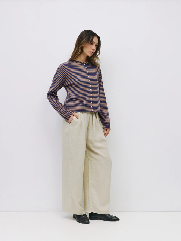 Woman wearing a striped shirt and beige pants against a white background