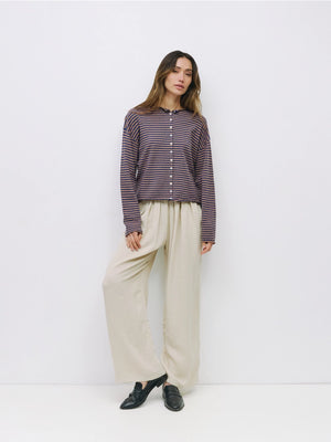 Woman wearing a striped shirt and beige pants against a white background
