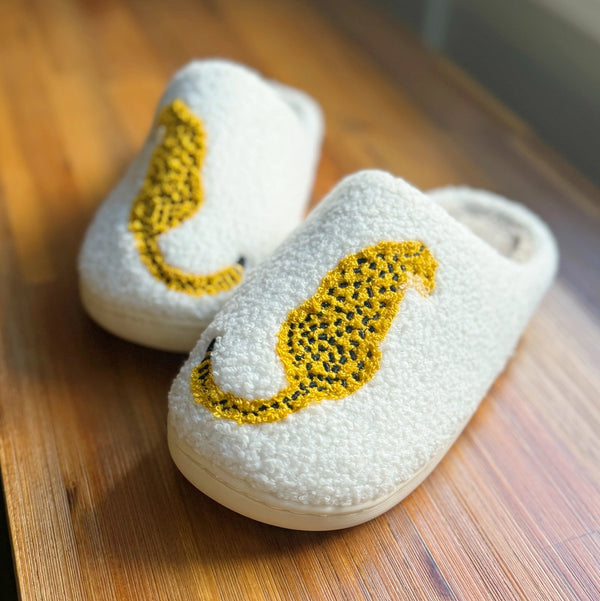 White slippers with cheetah print on a wooden surface