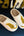 Pair of white slippers with yellow cheetah design on a dark surface