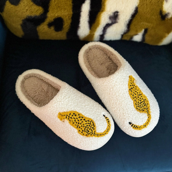 Pair of white slippers with yellow cheetah design on a dark surface