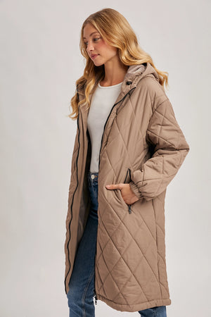 Woman wearing a beige quilted coat on a plain background