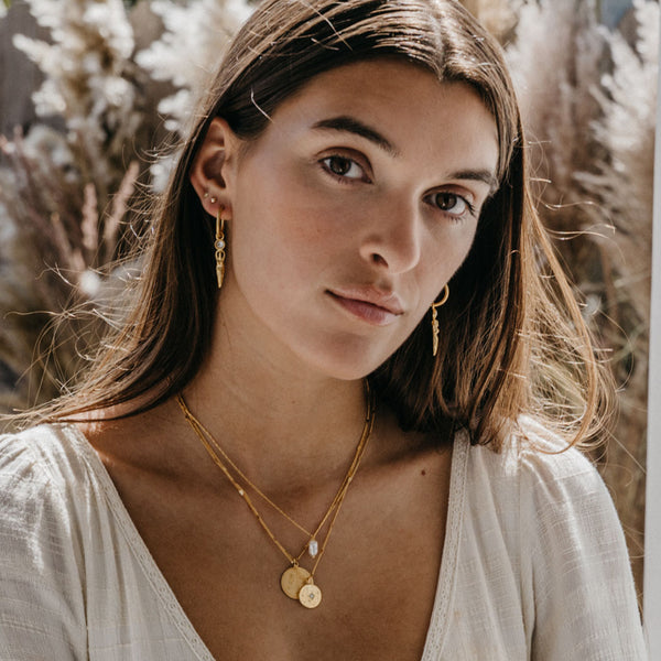 Woman wearing gold jewelry with a neutral background