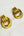 Pair of gold knot earrings on a light wooden surface