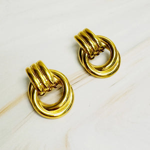 Pair of gold knot earrings on a light wooden surface