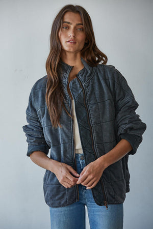 Woman wearing a dark quilted jacket against a plain background