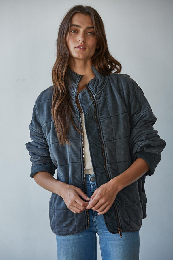 Woman wearing a dark quilted jacket against a plain background