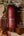 Kitsch hair perfume bottle on a wooden block with floral elements and fragrance notes text.